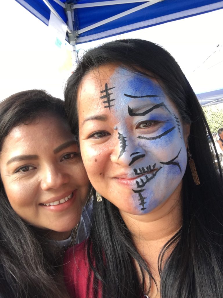 DCRC staff member Judith smiles with a happy attendee whose face was painted by Judith.