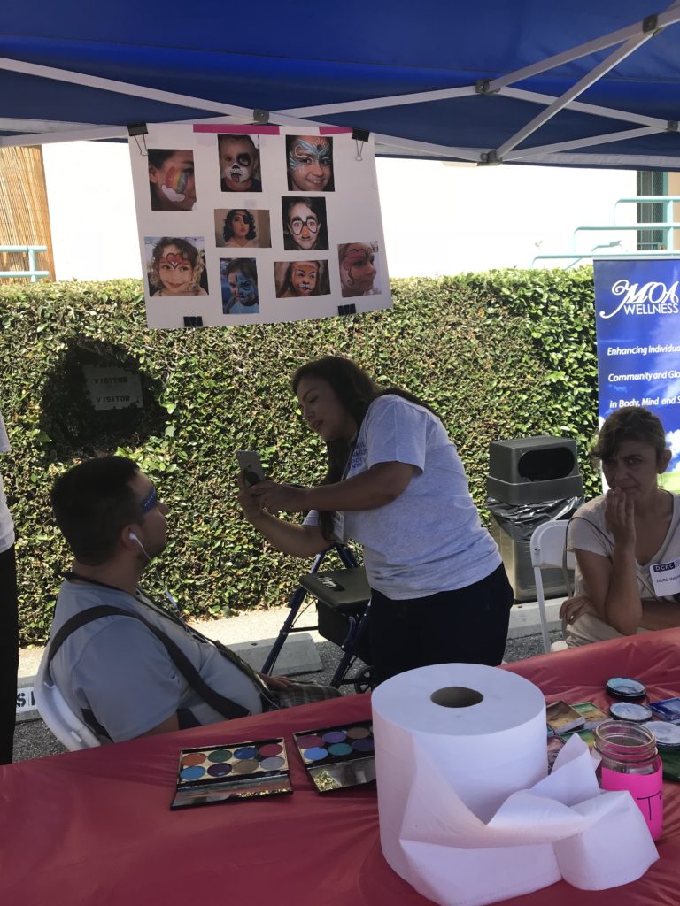 DCRC staff member Judith takes a photos for an attendee who just had their face painted.