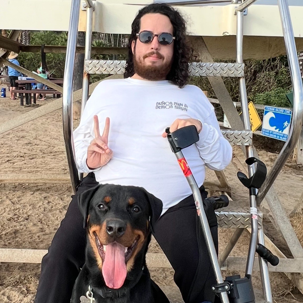 Tomas Leon sitting with his dog and his assistive crutches